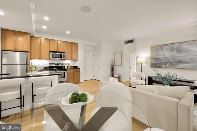 a kitchen with stainless steel appliances kitchen island granite countertop a refrigerator a stove a sink dishwasher and white cabinets with wooden floor