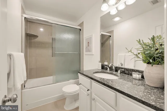 a bathroom with a granite countertop sink a toilet and shower