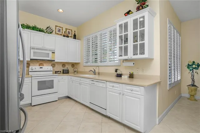 a kitchen with granite countertop white cabinets and white appliances