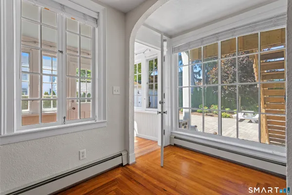 a view of an empty room with wooden floor and a window