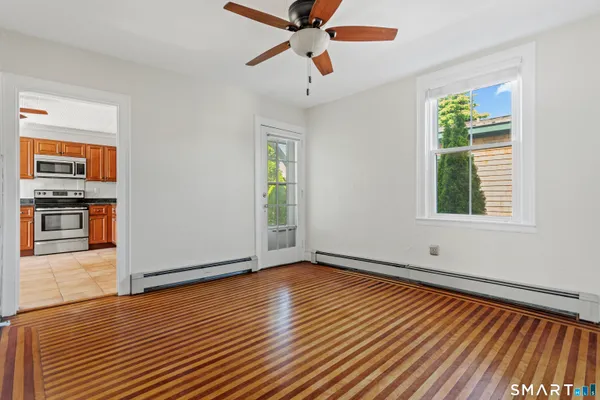 a view of an empty room with window and wooden floor