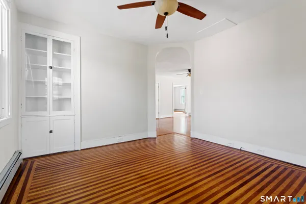 a view of an empty room with a window and wooden floor