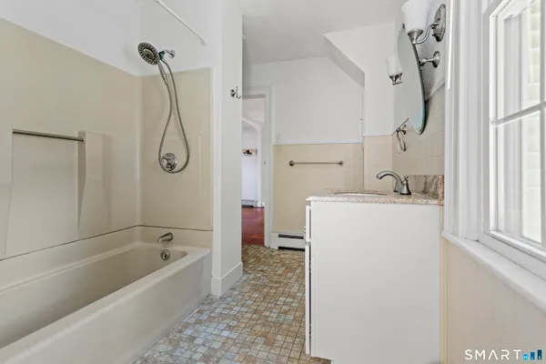 a bathroom with a tub sink a mirror and a shower