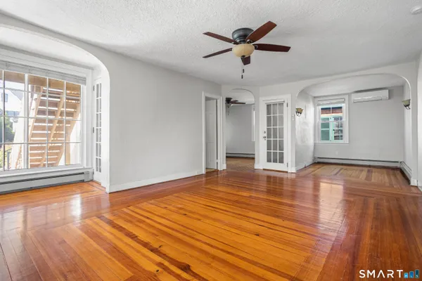 a view of empty room with wooden floor and fan