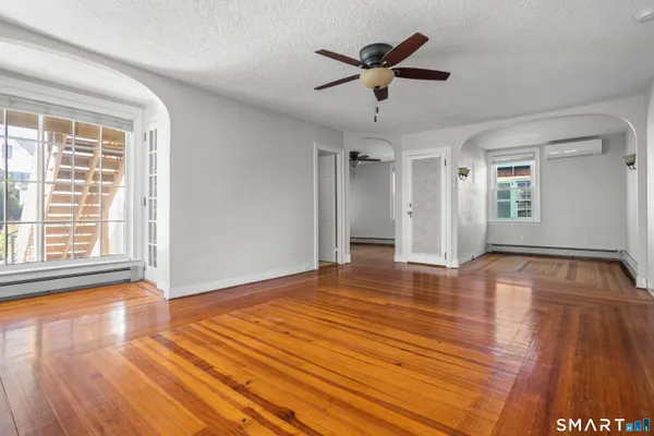 a view of empty room with wooden floor and fan