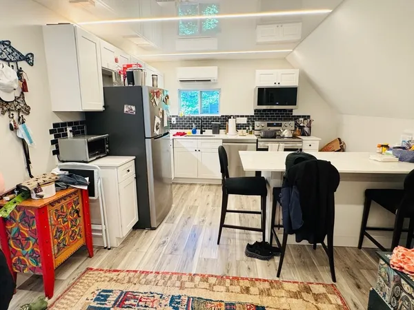 a kitchen with stainless steel appliances a stove top oven a sink dishwasher and a refrigerator with wooden floor