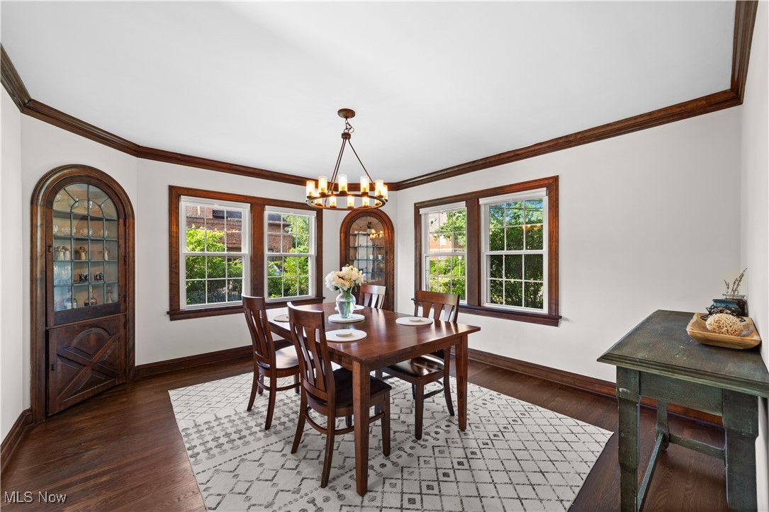 Dining room with a chandelier, ornamental molding, healthy amount of natural light, and wood finished floors