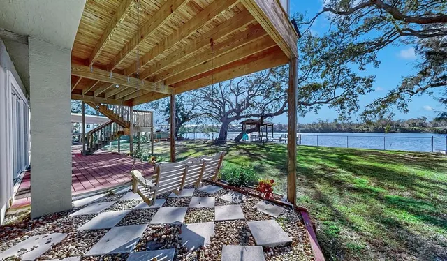 a large kitchen with stainless steel appliances granite countertop a refrigerator a sink dishwasher a stove and a dining table with wooden floor