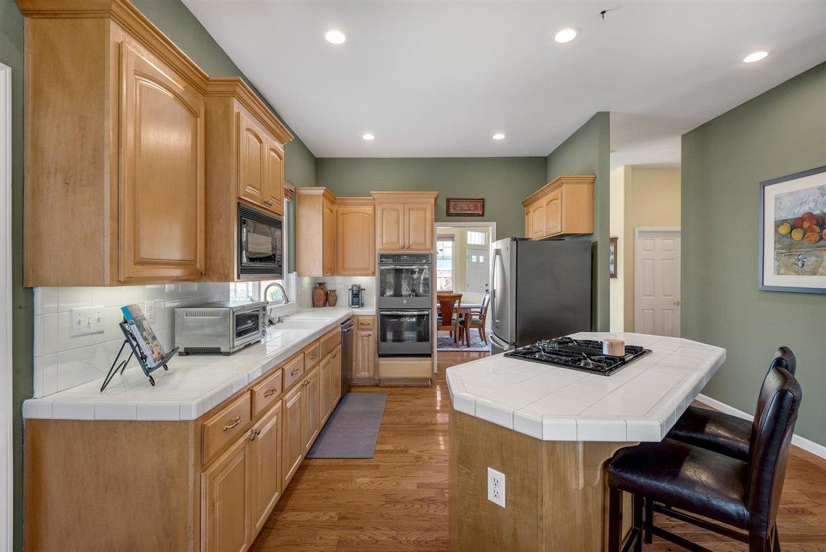1416 Casablanca Circle Gilroy, CA 95020 - Photo 4 of 32 a large kitchen with kitchen island a stove a sink a dining table and chairs