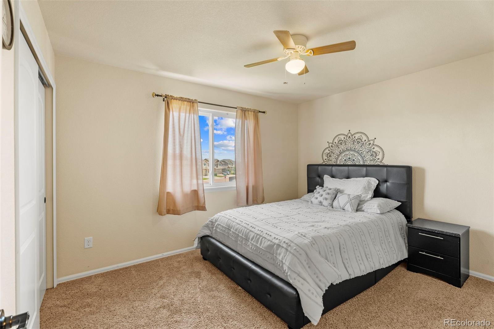 4651 Dancing Rain Way Colorado Springs, CO 80911 - Photo 14 of 32 a bedroom with a large bed and a ceiling fan