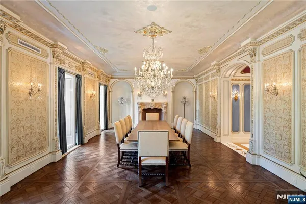 a dining room with wooden floor chandelier and glass door
