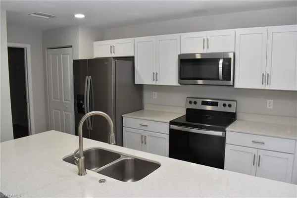 a kitchen with white cabinets a sink and stainless steel appliances