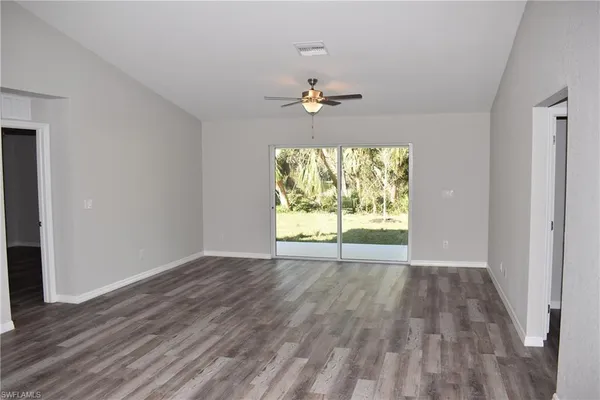 a view of an empty room with a window and wooden floor
