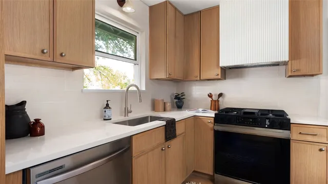 a kitchen with stainless steel appliances a stove a sink a cabinets and a window