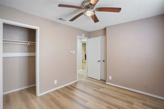 an empty room with closet and a ceiling fan