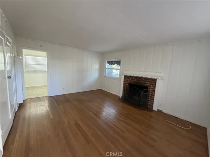 an empty room with wooden floor fireplace and windows