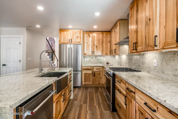 a kitchen with stainless steel appliances granite countertop a refrigerator a sink a stove and a wooden floors