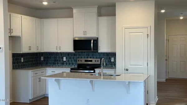 a kitchen with kitchen island granite countertop a sink and a stove top oven