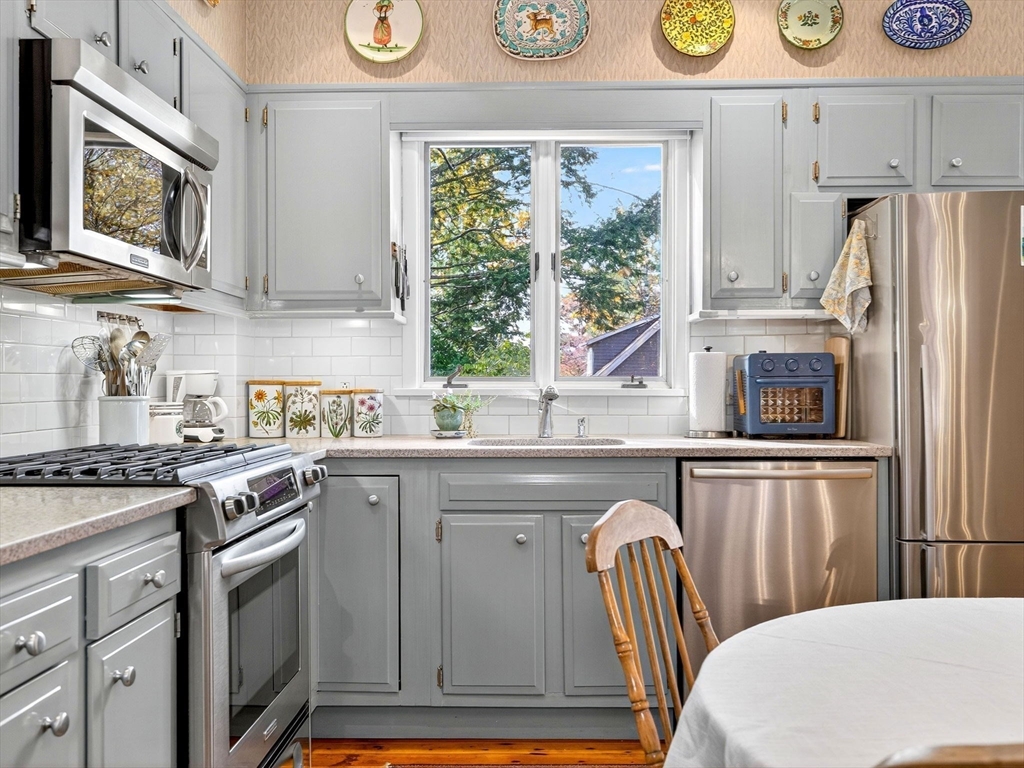 32 Donizetti Street Wellesley, MA 02482 - Photo 6 of 22 a kitchen with stainless steel appliances granite countertop a stove a refrigerator a microwave oven with a dining table and chairs