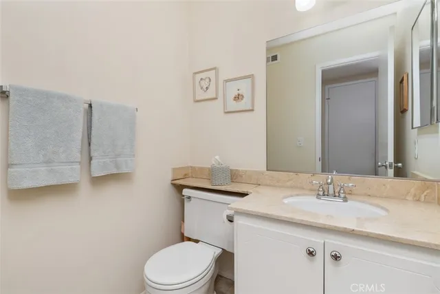 a bathroom with a granite countertop toilet sink and mirror