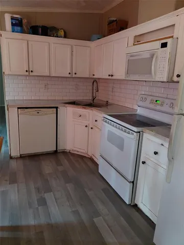 a kitchen with granite countertop white cabinets and white appliances