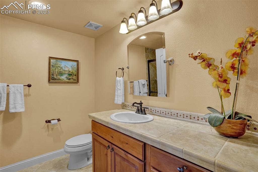 4655 Seton Hall Road Colorado Springs, CO 80918 - Photo 38 of 50 a bathroom with a granite countertop sink a toilet and a mirror