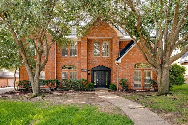 a front view of a house with a yard and tree s