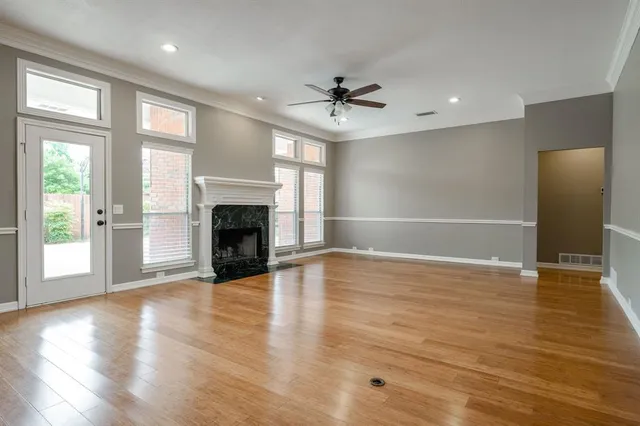 an empty room with wooden floor fireplace and windows