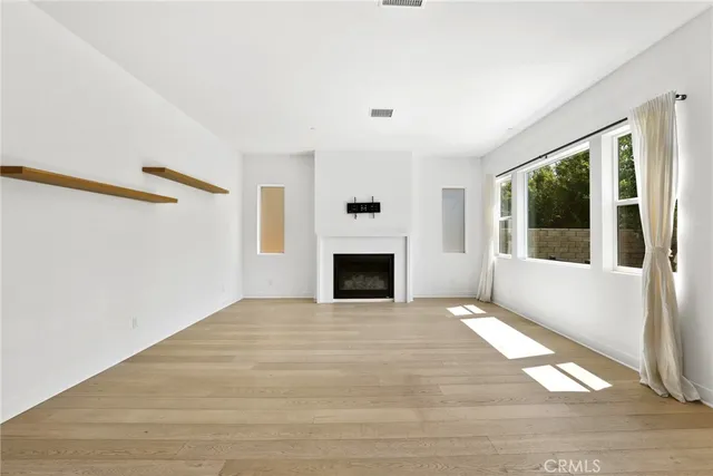 a view of an empty room with glass door and wooden floor