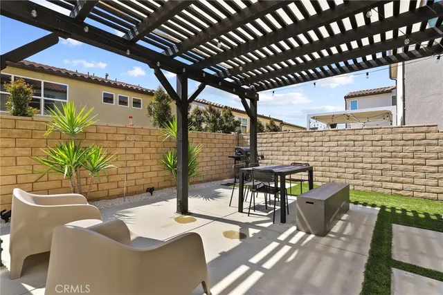 a view of a patio with couches table and chairs under an umbrella with a fire pit