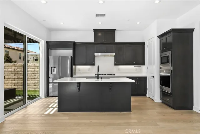 a view of kitchen with stainless steel appliances wooden floor and large window