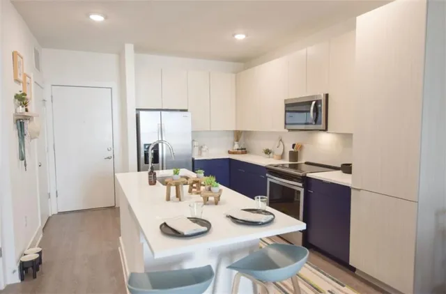 a open dining room with stainless steel appliances kitchen island granite countertop a table chairs and a refrigerator