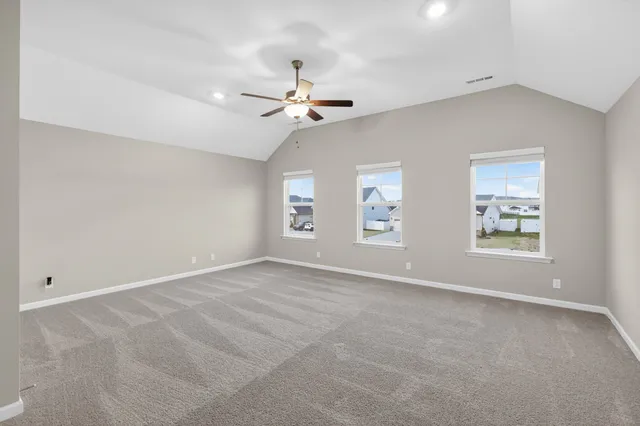 an empty room with windows and fan