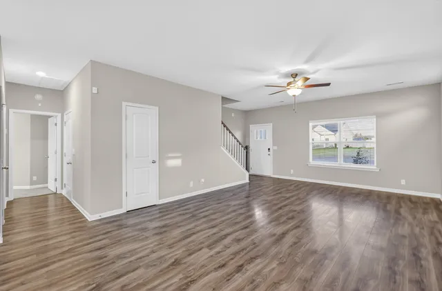 a view of an empty room with a window and wooden floor