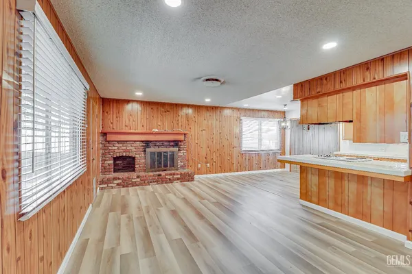 a open kitchen with granite countertop a stove top oven a sink dishwasher and a fireplace with wooden floor