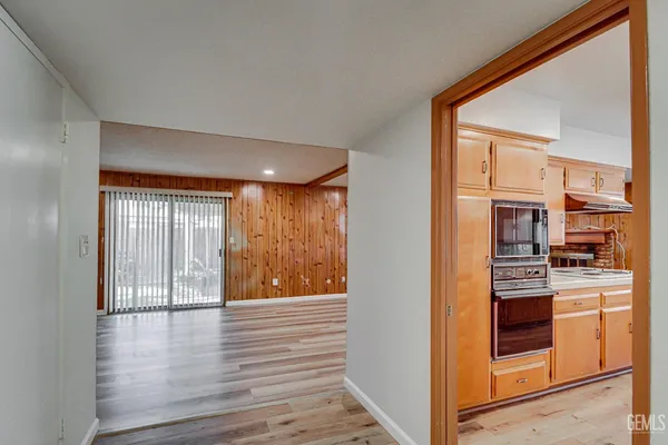 a view of a kitchen from an empty room with wooden floor and a window