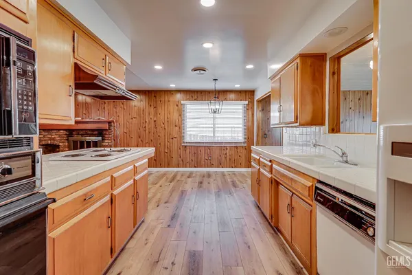a large kitchen with stainless steel appliances a large counter top a stove a sink and a refrigerator