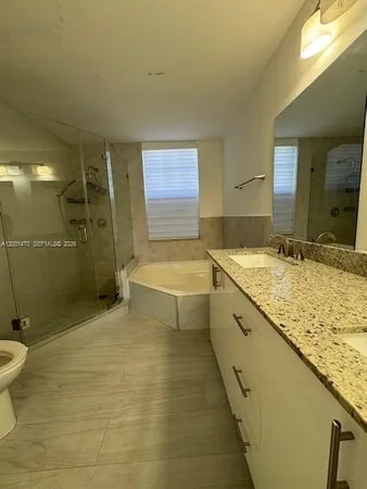 a bathroom with a granite countertop sink a toilet and shower