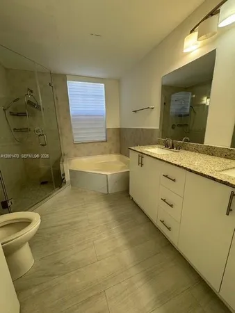 a bathroom with a granite countertop sink a toilet and bathtub