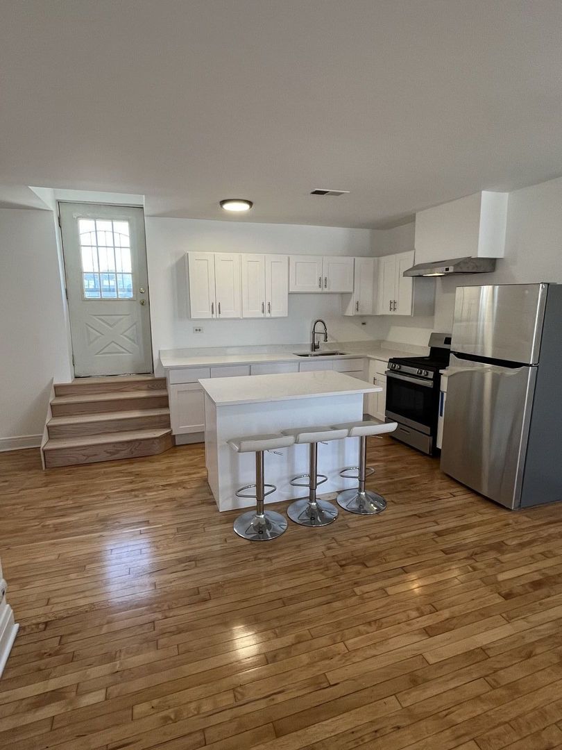 8016 South Halsted Street, Unit 2N Chicago, IL 60620 - Photo 2 of 13 a kitchen with kitchen island a sink stainless steel appliances and cabinets