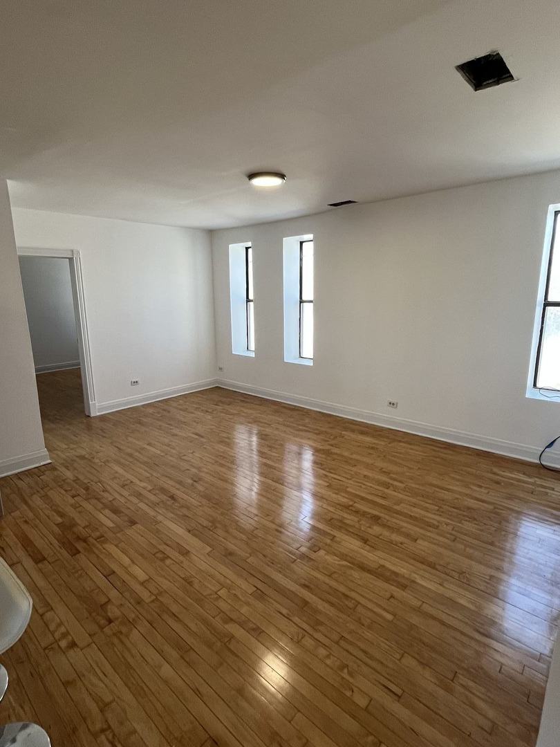 8016 South Halsted Street, Unit 2N Chicago, IL 60620 - Photo 4 of 13 an empty room with wooden floor and windows