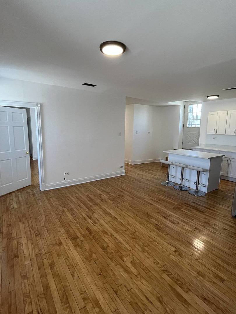 8016 South Halsted Street, Unit 2N Chicago, IL 60620 - Photo 5 of 13 a view of kitchen and empty room with wooden floor