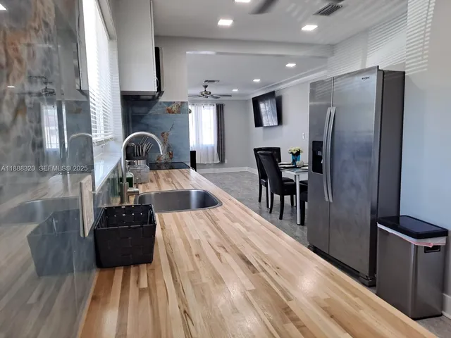 a kitchen with stainless steel appliances kitchen island granite countertop a refrigerator a stove and a sink with wooden floor