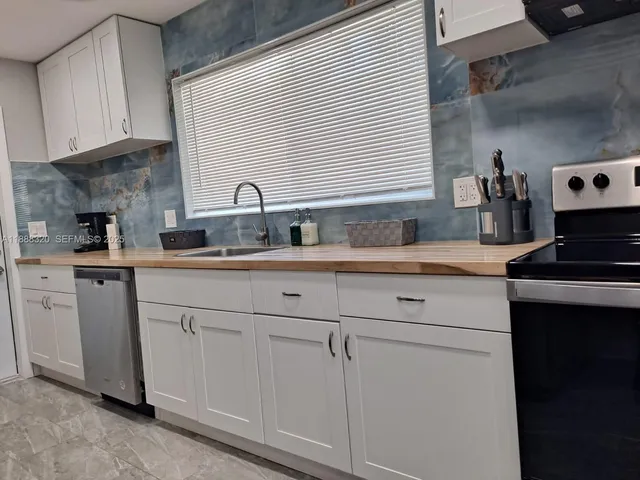 a kitchen with white cabinets and sink