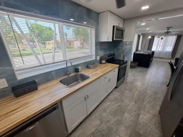 a kitchen with stainless steel appliances granite countertop a sink a stove and a wooden cabinets