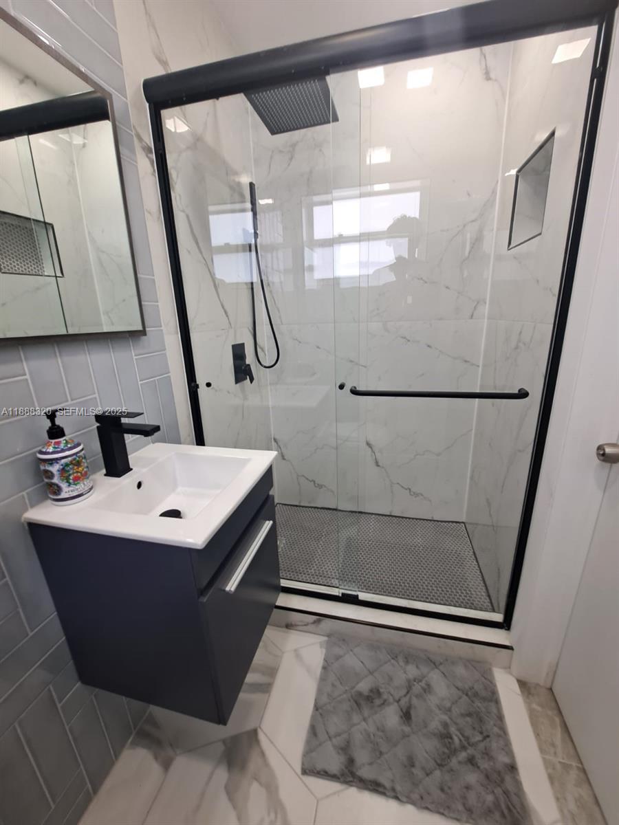 2242 Polk Street, Unit 1 Hollywood, FL 33020 - Photo 28 of 31 a bathroom with a sink a mirror and a shower
