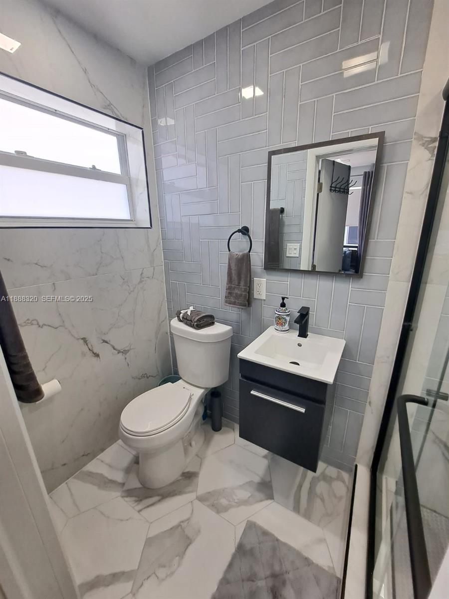 2242 Polk Street, Unit 1 Hollywood, FL 33020 - Photo 30 of 31 a bathroom with a sink toilet and mirror