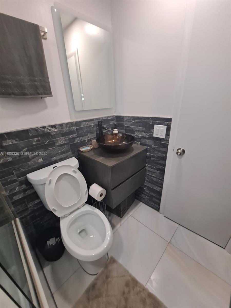 2242 Polk Street, Unit 1 Hollywood, FL 33020 - Photo 8 of 31 a bathroom with a toilet a sink and a mirror