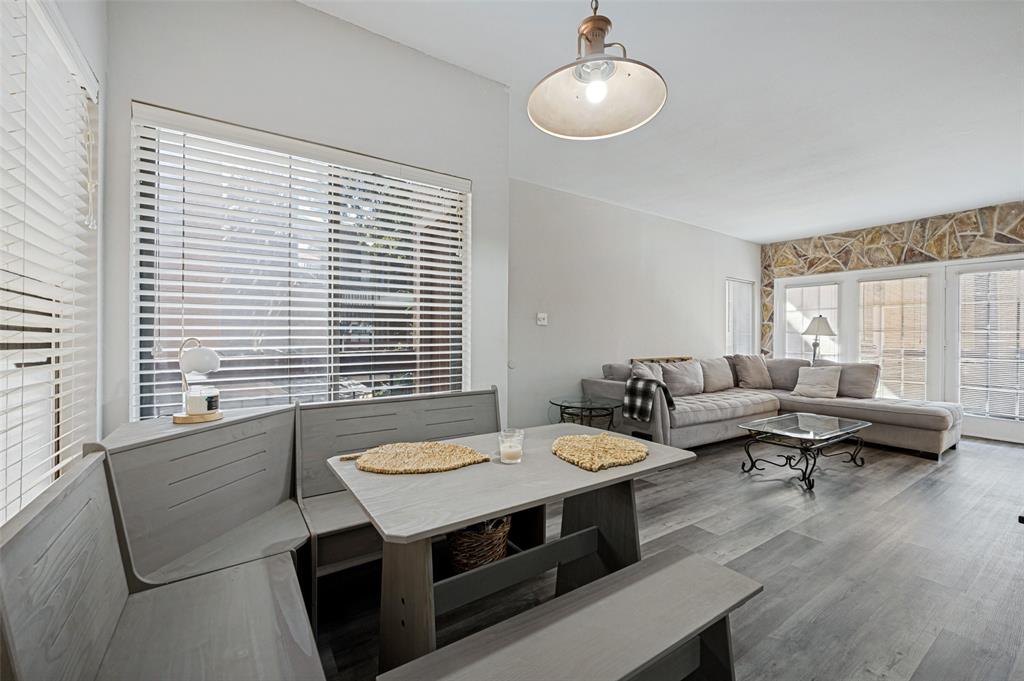 5550 Spring Valley Road, Unit C21 Dallas, TX 75254 - Photo 11 of 26 Wood-finish flooring throughout, vaulted ceiling, built-in banquette seating, stone accent wall, and multiple window panels