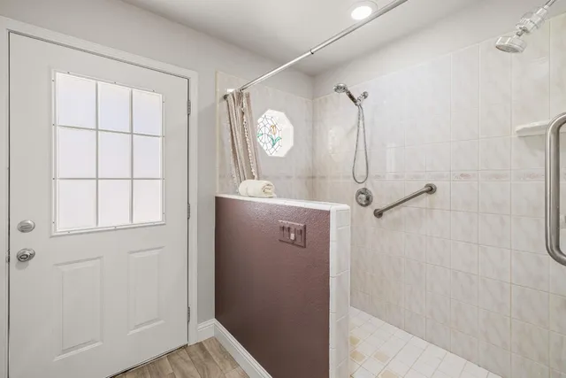 a bathroom with a shower a mirror and a window